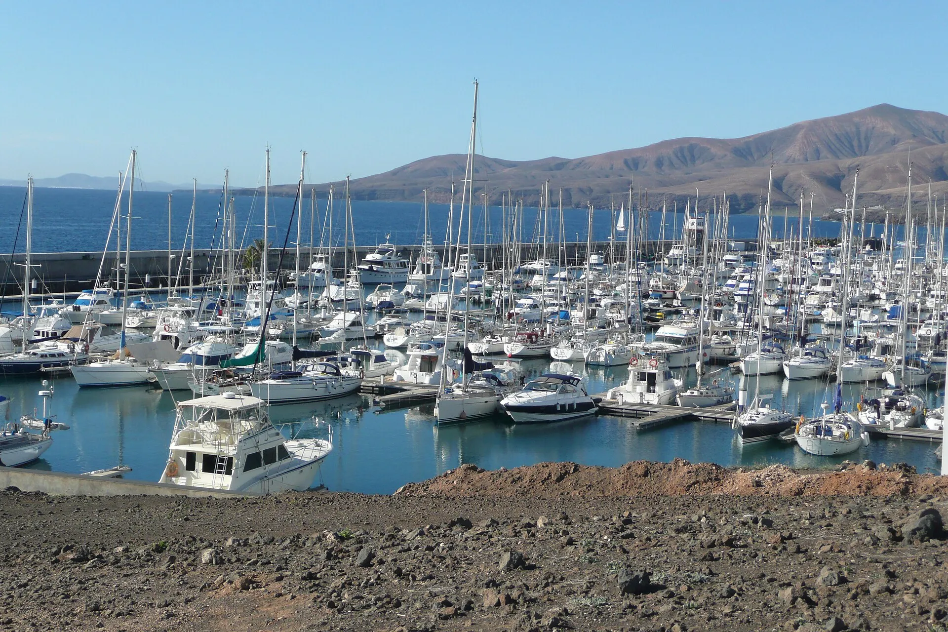 Yachts moored in the Puerto Calero marina, with the mountains of the south of the island behind