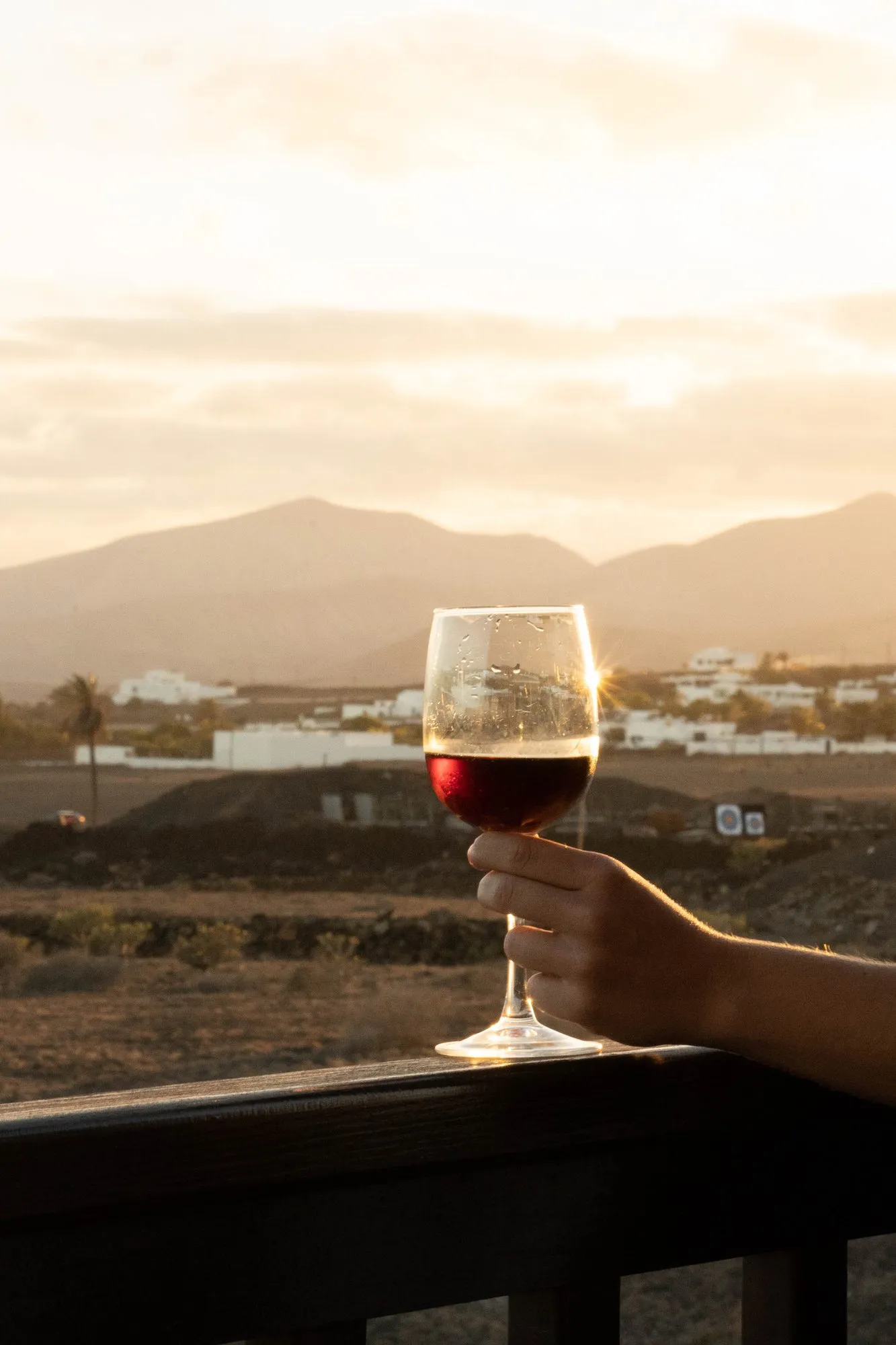 A glass of red wine at sunset, looking towards the volcanoes